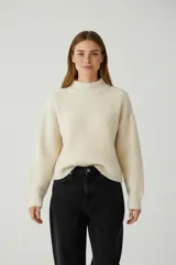 Sweater de algodón color crema, de punto acanalado, con cuello polera y diseño holgado de manga larga.