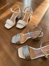 Sandalias de tacón cuadrado medio, con diseño de tiras finas y cierre de pulsera ajustable al tobillo. Confeccionadas en cuero sintético, presentan una punta cuadrada y un estilo minimalista y versátil.