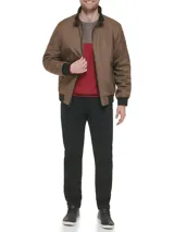 Campera bomber marrón de poliéster con cuello, puños y dobladillo elásticos negros. Cierre de cremallera frontal, bolsillos laterales con cierre y bolsillo en la manga izquierda.