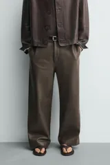 Pantalón de corte balloon fit confeccionado en piel, con bolsillos delanteros y traseros de vivo, cierre frontal con cremallera y botón.