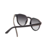 Lentes de sol Indie modelo Ozzy, con montura mixta de madera y acetato color negro y marrón. Lentes polarizados con filtro degradé gris.