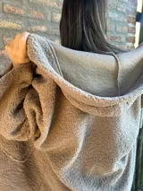 Campera de corderito color verde oscuro, con diseño holgado, cuello alto y manga larga. Presenta una etiqueta de cuero sintético en la manga.