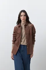Sobrecamisa de gamuza color marrón con bordados decorativos estilo western en la zona de los hombros y cierre frontal con botones metálicos.