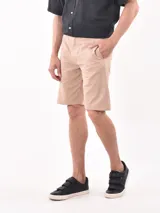 Bermuda de gabardina color beige, con corte recto, bolsillos laterales y cierre frontal.