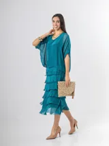 Vestido midi de seda italiana color negro, diseño dos en uno con capa superior de calce amplio, falda con volados y forro interior de algodón elastizado.