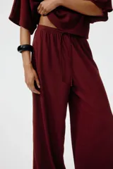 Pantalón de punto bordó de corte holgado con piernas amplias, tiro alto, cintura elástica y cordón ajustable.