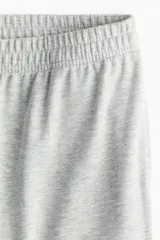 Pantalón deportivo gris claro de corte ancho, con cintura elástica y bolsillos laterales.