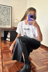 Pantalón Oxford de cuero negro con cierre frontal y pasamanería plateada en los tajos laterales.