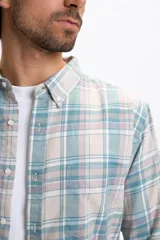 Camisa de manga larga con estampado de cuadros en tonos crudo, verde agua y lila. Presenta cuello camisero con botones, cierre frontal abotonado y un bolsillo en el pecho.