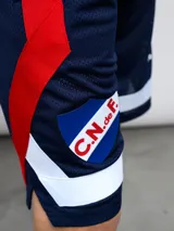 Short de básquet de malla (mesh) azul marino, con detalles en rojo y blanco en los laterales. Presenta el escudo del Club Nacional de Football y el logo de Umbro.