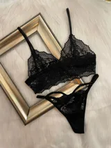 Conjunto de lencería de encaje negro compuesto por un top estilo bralette y una tanga colaless regulable. El top presenta breteles ajustables y diseño sin broches, confeccionado en encaje suave y elastizado.