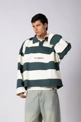 Buzo tipo polo de corte boxy con diseño de franjas horizontales anchas en color verde inglés y blanco. Presenta cuello camisero, cierre frontal parcial con botones ocultos y detalles de costuras expuestas con efecto desflecado. Incluye un pequeño logo estampado en el pecho.