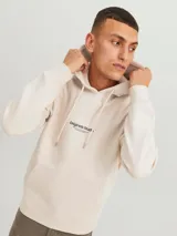 Canguro color beige con capucha, manga larga, calce relajado y bolsillo tipo canguro. Estampado frontal con la leyenda "Originals Studio BROUGHT TO YOU BY JACK&JONES DESIGNED IN COPENHAGEN".