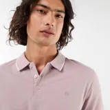 Remera polo de piqué color lila, con cuello camisero y ribetes blancos en el cuello y las mangas. Cuenta con cierre frontal parcial de dos botones y pequeño logo bordado en el pecho.