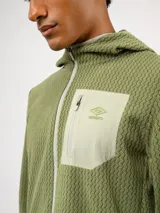 Campera de entrenamiento Umbro con capucha, cierre frontal completo y bolsillo en el pecho de nylon con cierre. Presenta una textura de tejido en relieve y logo de la marca estampado en el bolsillo.