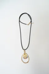Collar largo con cordón negro y dije colgante compuesto por tres piezas circulares superpuestas en tonos dorado, plateado y un elemento central de resina amarillenta.