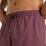 Short deportivo New Balance Essentials de 7 pulgadas, color violeta oscuro (ciruela/borgoña), con cintura elástica ajustable con cordón y logo NB pequeño en la pierna izquierda.