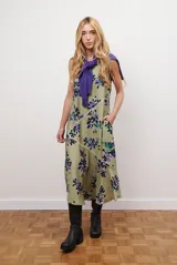 Vestido midi color beige con estampado de hojas en tonos violeta, verde y negro. Diseño sin mangas, con escote redondo y falda acampanada.