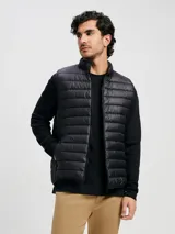 Chaleco puffer negro con cierre frontal, cuello alto y diseño acolchado horizontal.