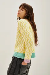 Sweater de punto con diseño de zigzag en tonos amarillo y blanco, cuello redondo, puños en color lila y ruedo en color verde menta.