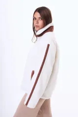 Campera de corderito sintético color blanco, con detalles en color marrón en el cierre, cuello y mangas. Posee cierre frontal y bolsillos laterales.