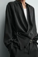Camisa de corte relajado confeccionada en tejido fluido con mezcla de viscosa y lyocell. Presenta cuello polo, manga larga con puños abotonados y un diseño cruzado con cierre frontal de botones.