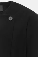 Blazer de cuello redondo y manga larga con volumen, color negro, de cierre cruzado con botones.