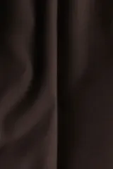 Pantalón sastrero de sarga en color marrón oscuro, con corte holgado, piernas amplias con raya marcada, cierre frontal con botón y corchete ocultos, bolsillos laterales al bies y bolsillos traseros insertados.