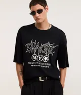Remera negra de algodón con textura y corte oversized. Presenta estampa frontal con lettering gótico, siglas 'NY' dentro de un círculo y coordenadas geográficas.