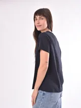 Remera negra de manga corta con estampado gráfico lineal en color blanco en el centro del pecho que incluye ilustraciones de frutas, copas brindando, una reposera y la inscripción "La Dolce Vita".