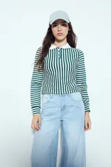 Remera de manga larga a rayas verticales verdes y blancas, con cuello polo y cierre frontal de botones. Presenta un diseño ajustado al cuerpo.