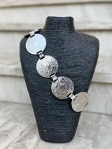 Cinto dorado de metal con eslabones y monedas circulares texturizadas.