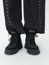 Borcegos de caña baja con diseño robusto, confeccionados en una combinación de gamuza y cuero sintético en tonos verde oliva. Presentan suela track de goma dentada en color suela, cordones al tono con ojalillos amarillos y cuello acolchado para mayor confort.