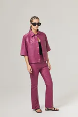 Pantalón de cuero rosa chicle, de corte recto, tiro medio, cierre lateral plateado y tajos en el dobladillo.