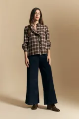 Camisa de algodón a cuadros con diseño de volados frontales, cuello alto y mangas largas con leve volumen.