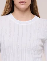 Blusa de punto acanalado fino, color negro, con ajuste al cuerpo, escote a la base y mangas largas. Cuenta con apliques de strass dispuestos en líneas verticales paralelas en el frente y las mangas, además de una vista decorada con estrás brillantes en el escote.