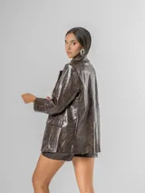 Blazer de mujer color marrón chocolate, confeccionado en ecocuero texturizado con acabado acharolado. Es forrado y presenta un corte estructurado con solapas y bolsillos frontales.