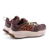 Championes de trail running New Balance modelo Hierro v8, color bordó con detalles en naranja y suela clara. Presentan tecnología de amortiguación Fresh Foam X en la mediasuela y suela Vibram Eco-Step Natural para mayor tracción y durabilidad en terrenos irregulares.