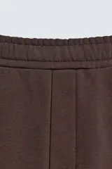 Pantalón jogger de algodón color marrón oscuro, de corte relajado y pierna ancha. Presenta cintura elástica con cordón ajustable y bolsillos laterales y uno trasero de plastrón.