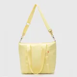 Bolso tipo tote de diseño acolchado en color amarillo, con doble asa de mano y correa larga ajustable y extraíble. Presenta el logo de la marca grabado en el frente y una pequeña etiqueta decorativa lateral.