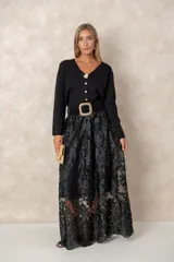 Cardigan de punto fino color negro con escote en V, manga larga y cierre frontal con botones dorados labrados, destacando un botón joya superior en forma de flor.