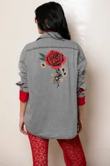 Camisa de jean gris con corte oversize y mangas largas. Presenta un bordado detallado en la espalda que incluye una rosa roja grande, flores pequeñas y una abeja.