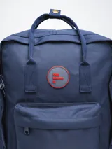 Mochila color verde militar con diseño clásico y minimalista. Cuenta con un compartimento principal con cierre de doble cremallera, un bolsillo frontal con cierre y dos asas superiores con broche. En el frente, tiene un parche circular con el texto "FORUM INDUSTRIES CO." en rojo.