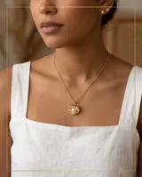 Collar de bronce con cadena fina dorada y dije en forma de ostra marina abierta que contiene una perla en su interior.