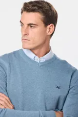 Suéter de tejido fino color azul marino, con cuello en V y manga larga. Presenta un pequeño logo bordado en el pecho.