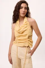 Top amarillo con cuello halter, frunces y jaretas ajustables en el frente. Espalda descubierta. Confeccionado en lino y algodón.