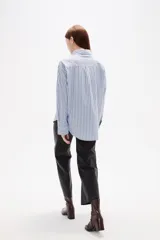 Camisa de algodón con diseño de rayas verticales finas en tonos neutros, corte holgado, cuello camisero y cierre frontal con botones.