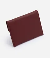Billetera tipo sobre Satinato color bordó, de formato compacto y estructura plegable. Con textura en relieve, solapa frontal y aplique metálico triangular con el nombre de la marca grabado.