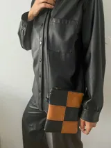 Bandolera pequeña con diseño de tablero de ajedrez en cuero sintético color negro y marrón.
