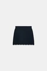 Minifalda de tiro alto en tejido de punto negro, con cintura elástica y diseño de bajo con terminación en ondas.